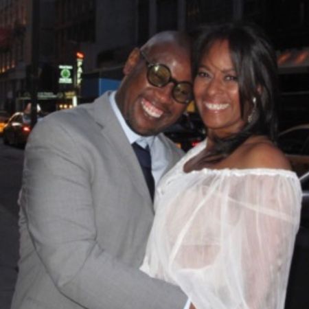 Wendy Credle in a white dress poses a picture with Andre Harrell.